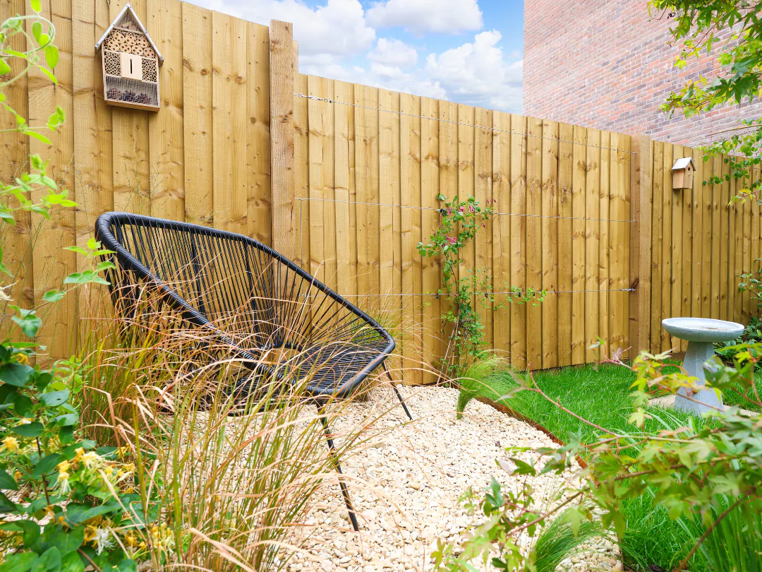 Outdoor seating area surrounded by luscious greenery and fence climbing plants.