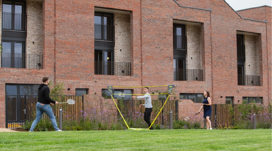 Three people playing a casual game of badminton on the shared green park at Brabazon, Bristol.