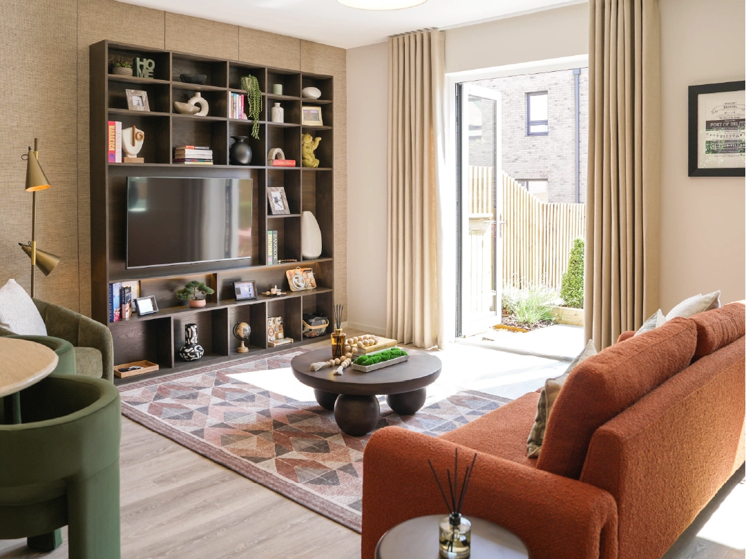 Modern living room featuring a custom TV shelf, orange sofa, patterned rug, and natural light streaming in through open doors.