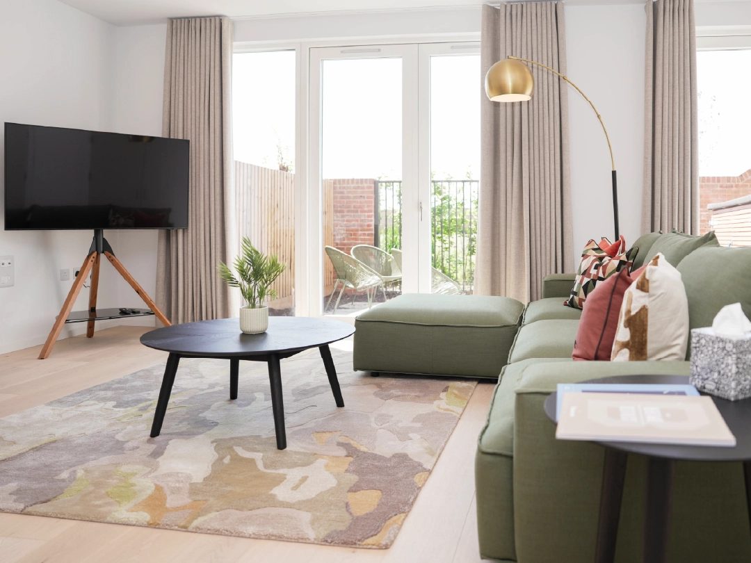Bright and light living room, showcasing large 3-seated sofa, coffee table and television. 