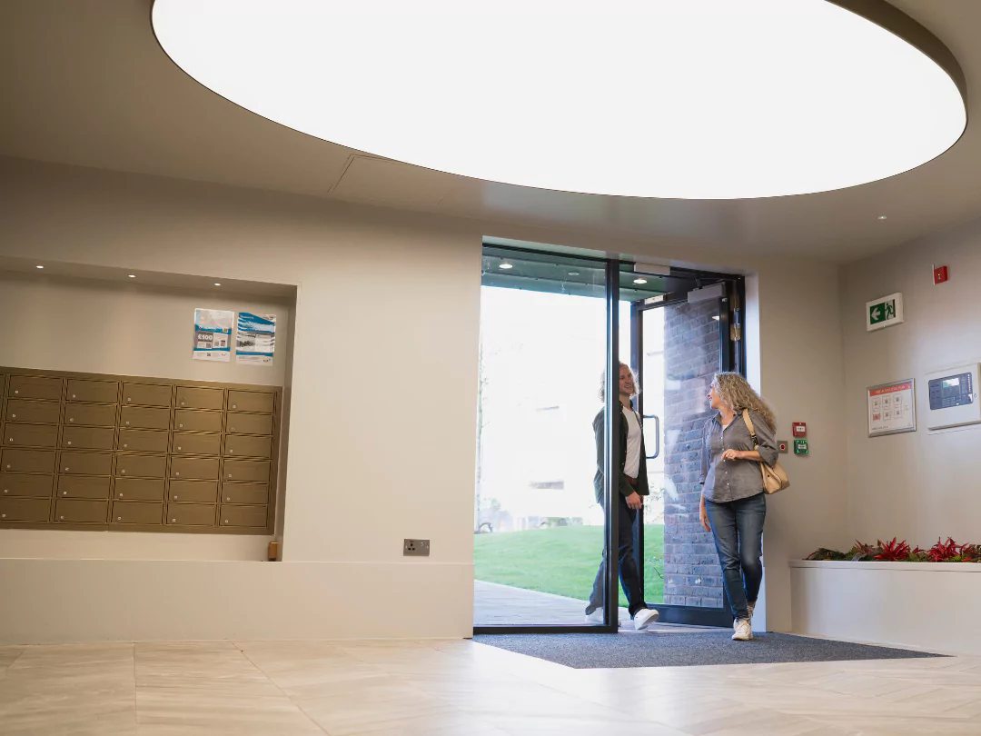 Couple smiling and talking while walking into the foyer of a luxury apartment building.