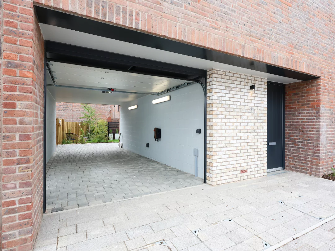 Pictured is a red brick car port including a electric car charger.