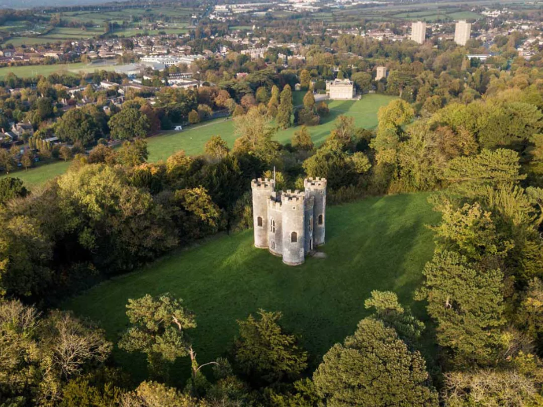 Ariel shot of Blaise Estate, with a castle in the centre of a grassy hill surrounded by trees. 