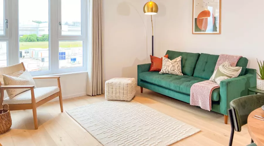 Bright and welcoming living-dining space with a green sofa, armchair and warm wood flooring