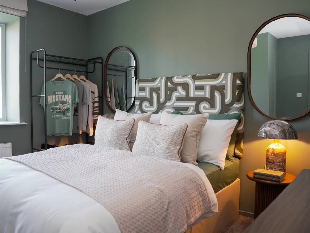 Cozy and modern secondary bedroom at Brabazon, with white bedding and a cool teal wallpaper. 