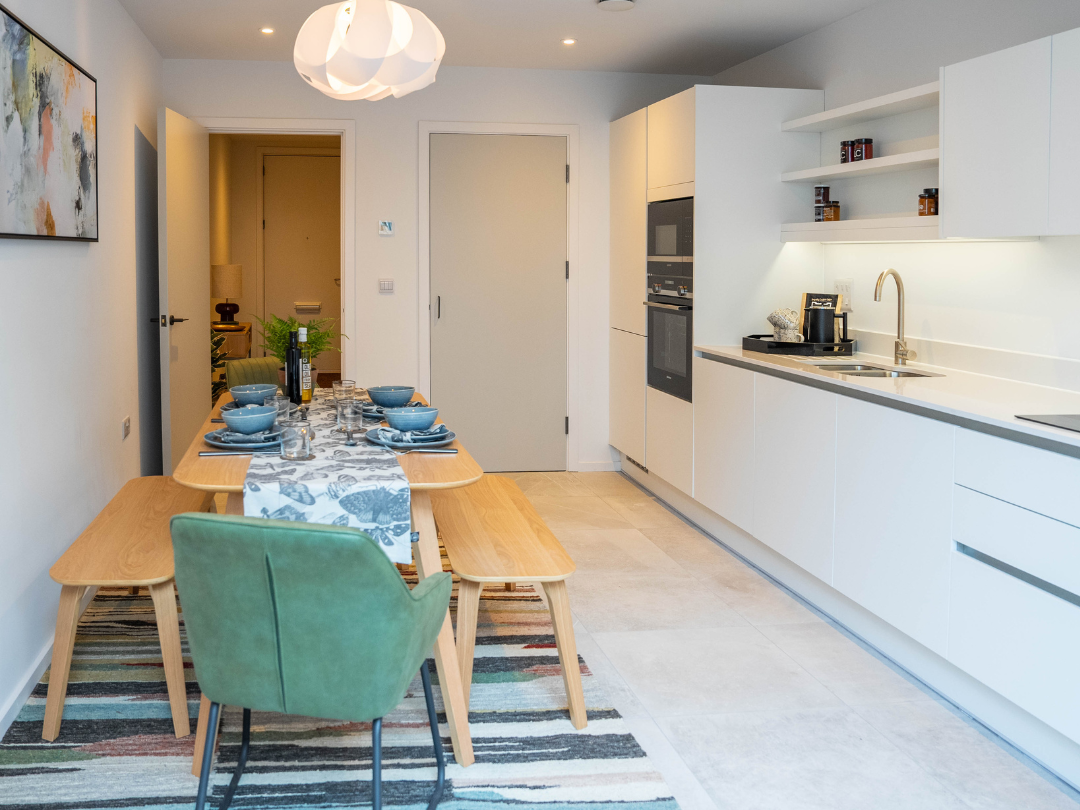 Bright kitchen-diner with modern white kitchen down one wall and a dining table.